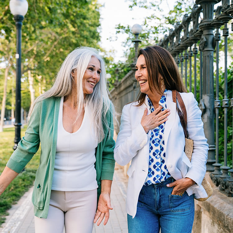 Two women laughing while walking outdoors